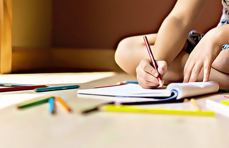 kid journaling in a notebook sitting crossed-legged on floor with colored pencils